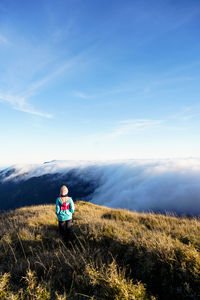 Rear view of woman walking on field against sky