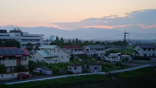 Houses in town against sky during sunset