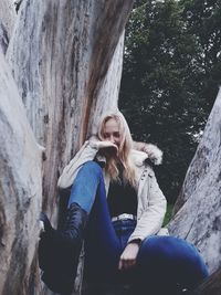 Low angle view of young woman sitting on tree