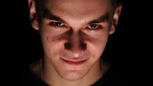 Close-up portrait of mid adult man against black background