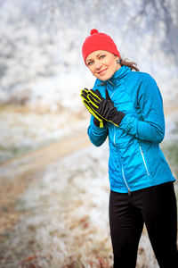 Portrait of mid adult woman standing on snow covered field in forest