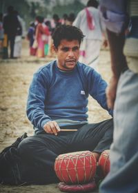 Rear view of man sitting on sidewalk