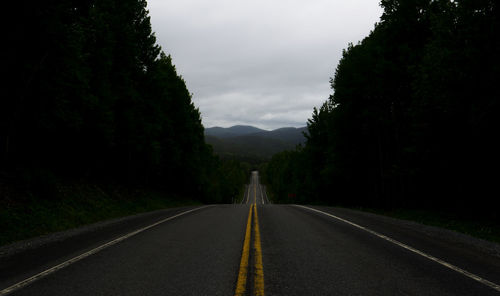 Road amidst trees against sky