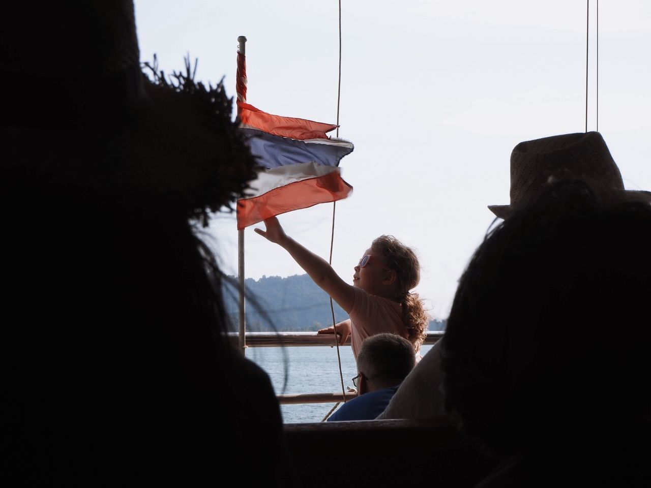 REAR VIEW OF PEOPLE SITTING ON BEACH