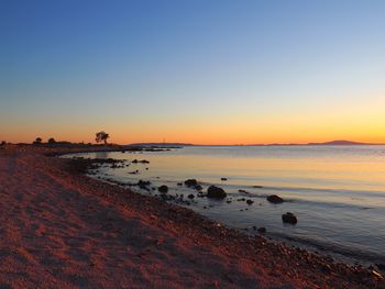 Scenic view of beach against clear sky during sunset