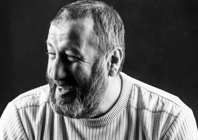 Portrait of a smiling gray bearded armenian on a dark gray background black and white photo