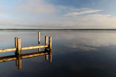 Wooden post in sea against sky