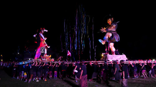 People standing by illuminated lights at night