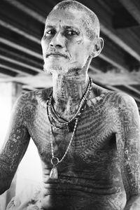 Portrait of shirtless tattooed man at home