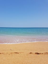 Scenic view of beach against clear blue sky