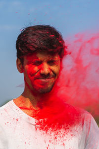 Young man playing holi against sky