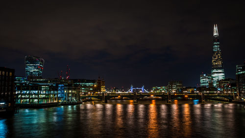 Illuminated shard london bridge and cityscape by thames river at night