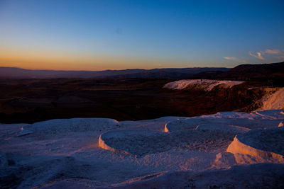 Scenic view of snowcapped mountains against clear sky during sunset