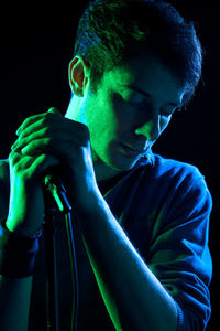 Close-up of man singing against black background