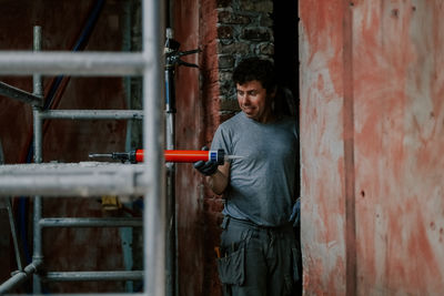 A male builder takes a gun with silicone for repairs. person
