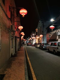 Illuminated street amidst buildings in city at night