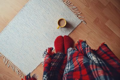 Low section of woman with coffee mug on hardwood floor at home