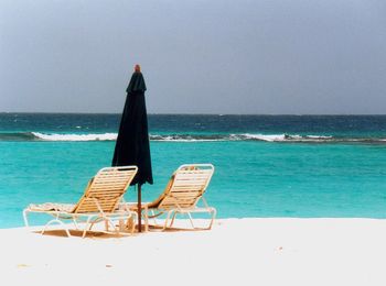 Deck chairs on beach against clear sky
