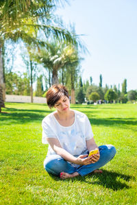 Full length of woman using smart phone while sitting at park