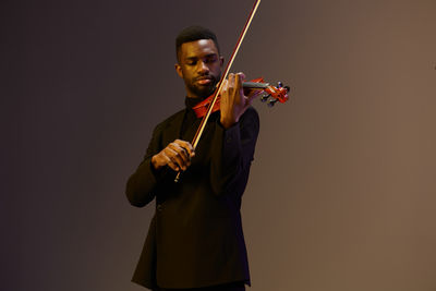 Midsection of man playing violin against black background