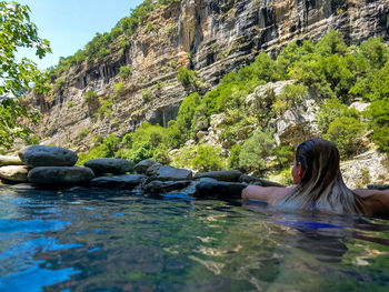 Rear view of woman in lake against mountain