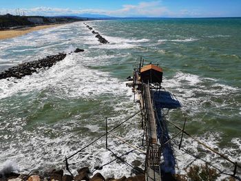 High angle view of wooden posts in sea against sky