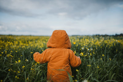 Rear view of girl standing by flowering plants