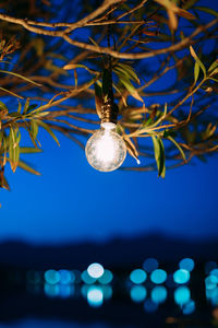 Low angle view of illuminated light bulb against sky at dusk