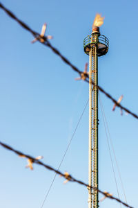 Low angle view of barbed wire against tower