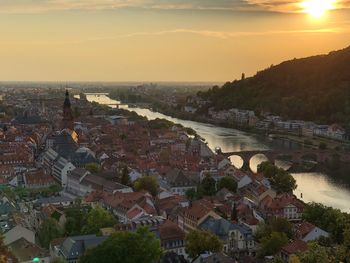 High angle view of townscape by river at sunset