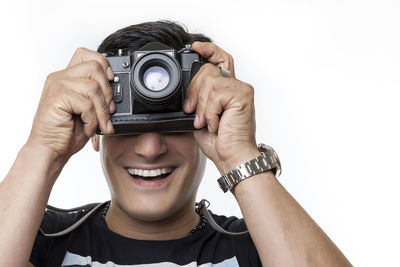 Portrait of man holding camera against white background