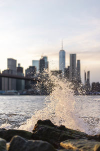 Water splashing on modern buildings in city against sky