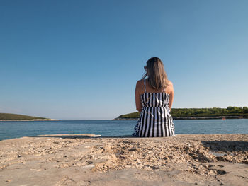 Rear view of woman looking at sea against clear sky