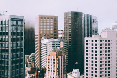 Buildings in city against foggy sky