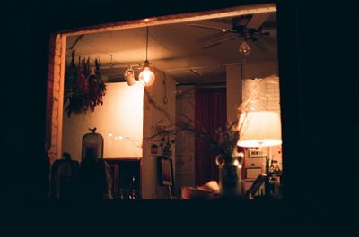 Illuminated lamp hanging on ceiling at home