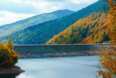 Scenic view of lake by mountains against sky