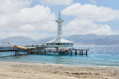 Lighthouse by sea against sky