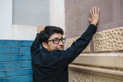 Young transgender person smiling while posing standing outdoors.