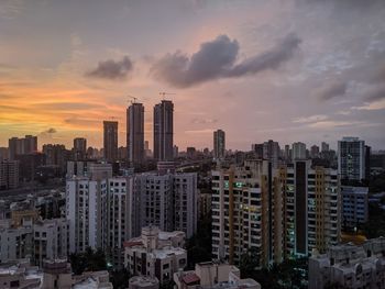 Modern buildings in city against sky during sunset