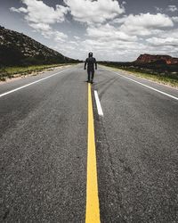 Rear view of man riding motorcycle on road