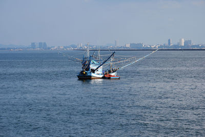 Ship sailing in sea against sky in city