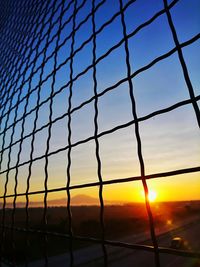 Low angle view of silhouette fence against sky during sunset