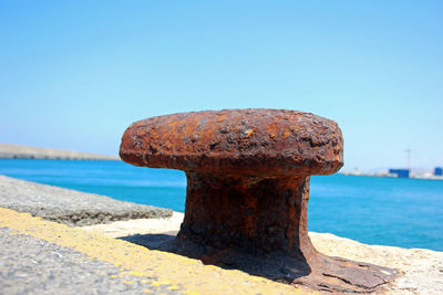 Close-up of rusty metal on beach against clear sky