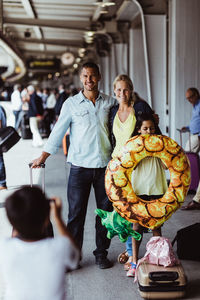 Boy photographing family holding luggage while standing at railroad station