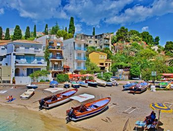 Boats moored at beach by buildings against sky