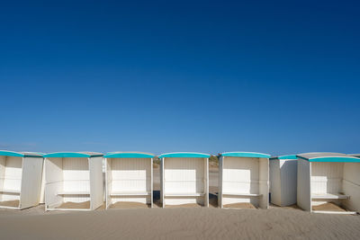 Chairs on beach against clear blue sky