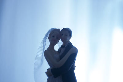 Close-up of wedding cake figurine against window at home