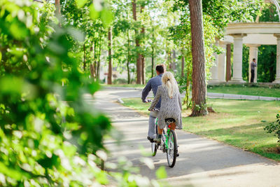 Rear view of couple cycling on road