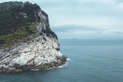 Rock formation in sea against sky