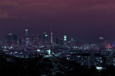 Illuminated buildings in city against sky at night